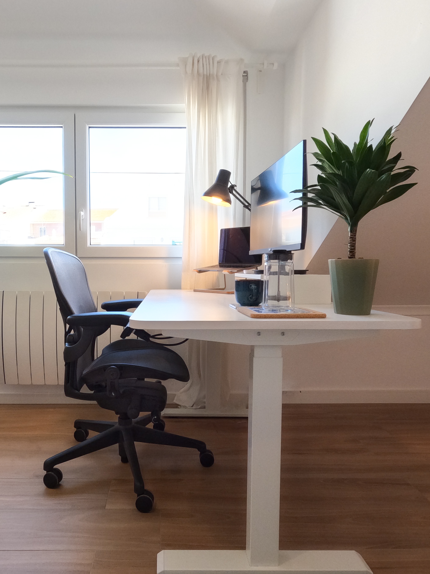 Height-adjustable standing desk with Herman Miller chair and monitor