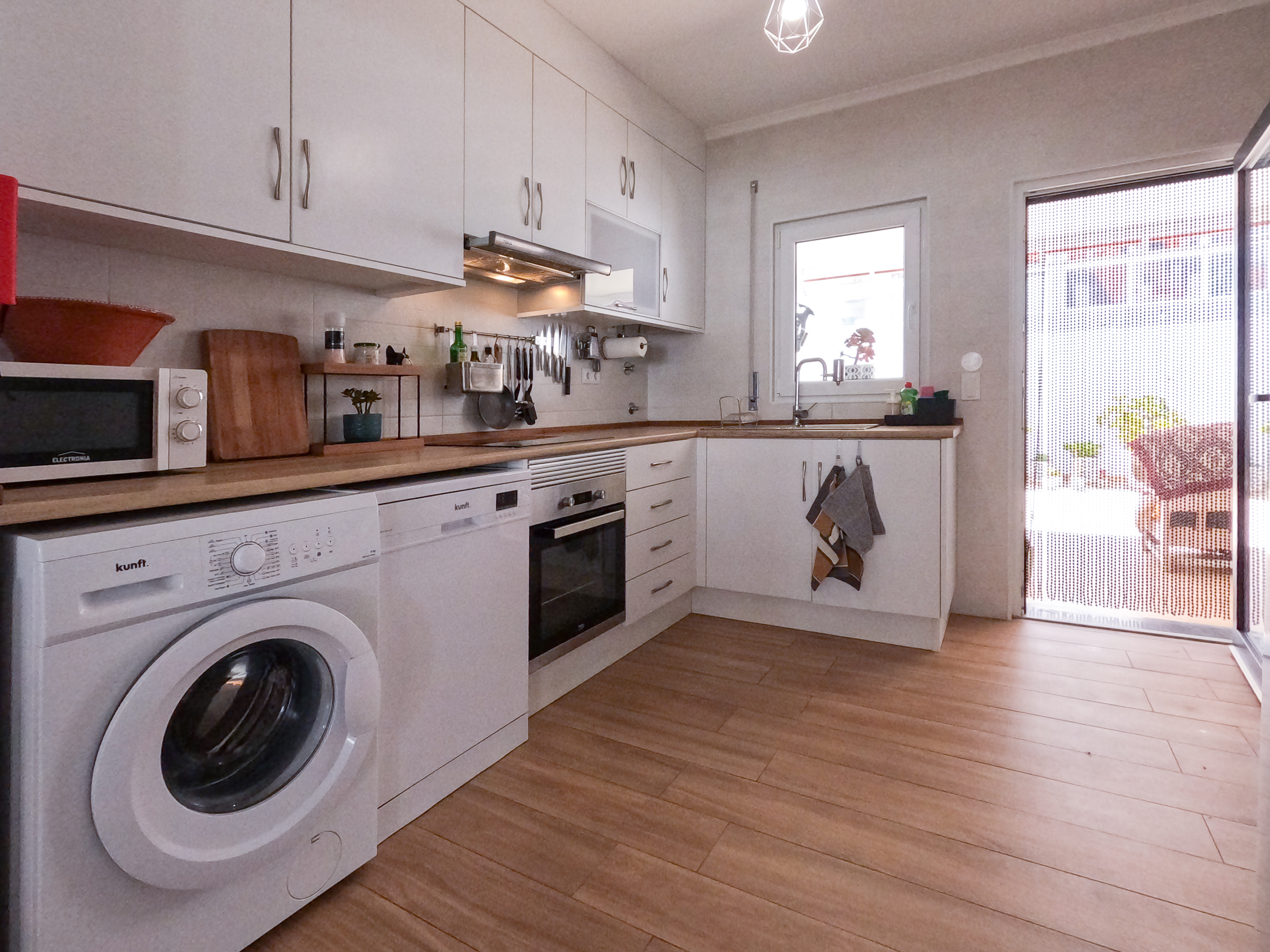 Fully equipped kitchen with oven, washing machine, and natural light